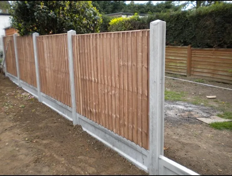 Closeboard timber fence panels on concrete posts mid-installation, with a string line stretched along the run