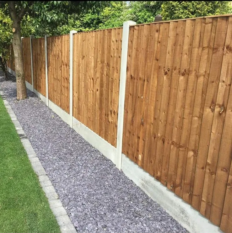 Finished closeboard timber fence on concrete posts beside a slate chipping border and lawn