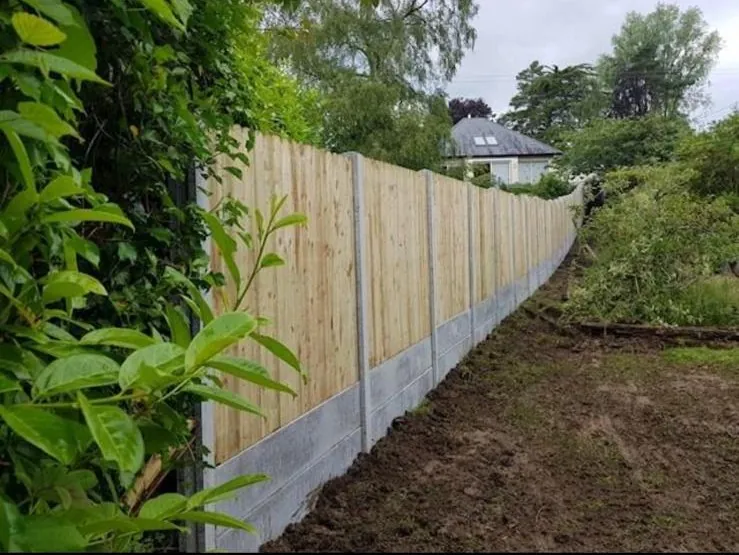 A long run of pressure-treated timber fencing on concrete posts and gravel boards along a rural boundary